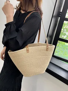 Large beige woven straw tote bag with brown leather handles for summer beach vacations