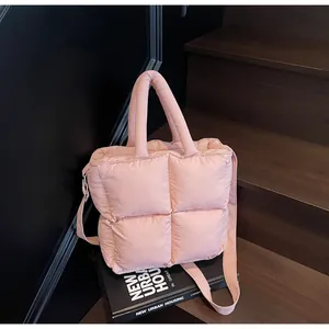 Detailed shot of pink quilted puffer handbag on books showing soft texture and straps