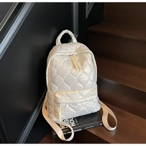 Detail of white quilted down backpack featuring glossy texture and diamond stitching