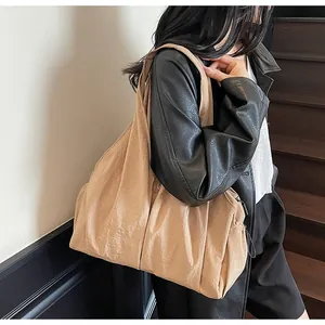 Detailed view of the large pleated beige shoulder bag with natural glossy fabric texture
