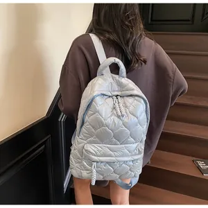 Detailed view of light blue quilted backpack with heart stitching on shiny nylon fabric