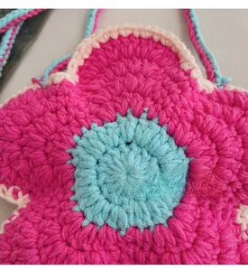 Detailed macro view of handmade crochet flower bag with vibrant pink and blue yarn texture