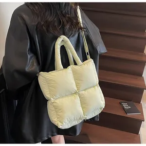 Detail of light green quilted down tote bag with soft padded texture and crossbody strap