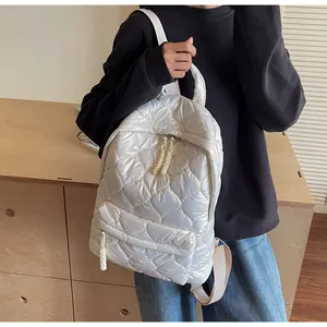 Detail of white quilted puffer backpack showing diamond stitching and woven zipper pull