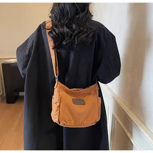 Detailed back view of a caramel canvas messenger bag with a gray leather logo patch
