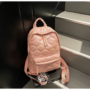Detailed view of pink quilted down fabric backpack featuring heart-patterned stitching