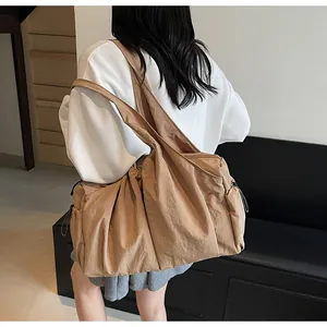 Macro detail of khaki pleated nylon tote bag with drawstring and wide shoulder strap
