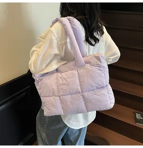 Close-up of a light purple quilted puffer tote bag worn by a model on wooden stairs
