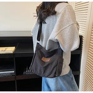 Detail of durable black canvas crossbody bag with brown leather label and wide strap