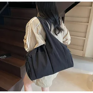 Detailed view of oversized black pleated tote bag with wide strap on model