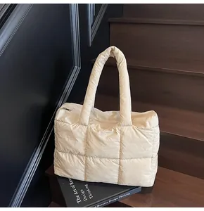 Detail of beige quilted down tote bag with soft padded texture and top zipper closure