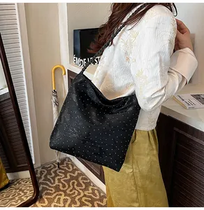 Detail of black tote bag with white polka dots and unique woven shoulder strap design
