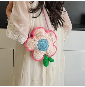 Detailed view of handmade crochet flower bag with pink petals and green knitted strap