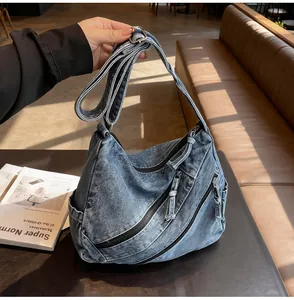 Detail of blue denim tote bag with three diagonal zipper pockets and wide shoulder strap