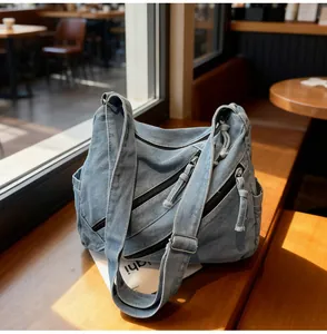 Detail of light blue denim tote bag with multiple zipper pockets and adjustable strap