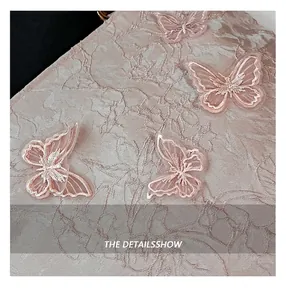 Detailed view of champagne pink silk fabric with 3D butterfly embroidery on the handbag