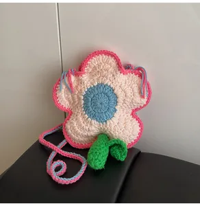 Close-up of handmade crochet flower bag with pink edges, white petals, and green leaf detail
