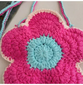 Detailed macro view of handmade crochet flower bag with pink petals and blue center