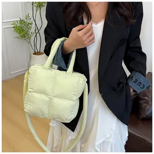 Macro view of light yellow quilted down handbag with soft square puffer texture and strap