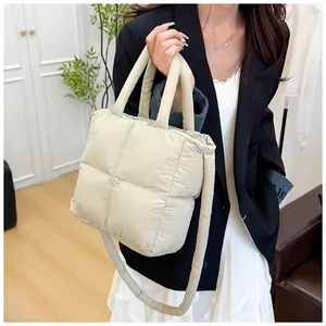 Detail of a beige quilted puffer bag with soft padding and double top handles