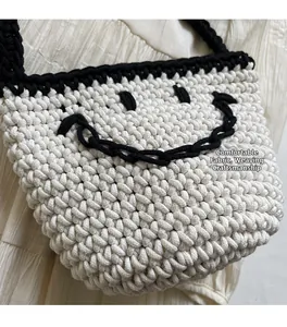Primer plano detallado del bolso de hombro tejido marfil con diseño de carita sonriente