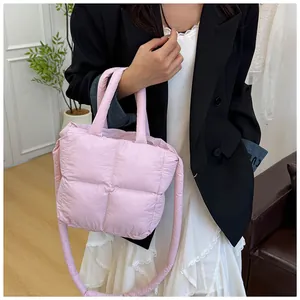 Detail of pink quilted down puffer handbag with dual handles and crossbody strap