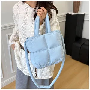 Detailed view of light blue quilted puffer bag with crossbody strap and padded handle