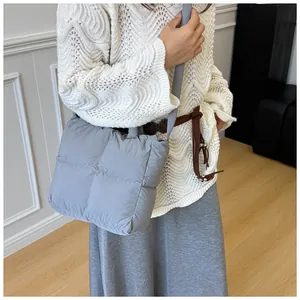 Close-up of light blue quilted down padding tote bag with soft texture and wide shoulder strap