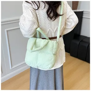 Detail of light green quilted down tote bag with soft texture and matching strap