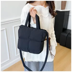 Detail view of a black quilted puffer tote bag with handles and a long shoulder strap