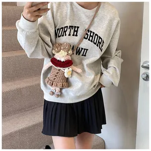Gros plan détaillé d'un sac poupée en crochet fait main avec bouton perle et dentelle
