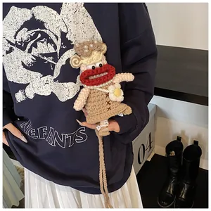 Détail du sac poupée au crochet avec de grandes lèvres rouges et collier de perles