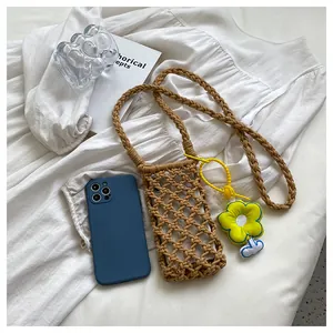 Close-up of handwoven hollow brown crossbody phone bag with yellow flower charm