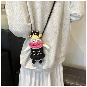 Detail of handcrafted crochet doll bag featuring pink lips and pearl accents on a grey hoodie