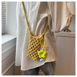 Detail of yellow hollow hand-woven crossbody phone bag with a floral charm