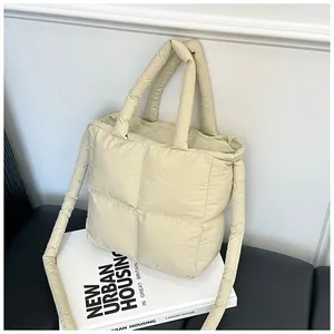 Detailed close-up of a beige quilted puffer tote bag with a soft handle and square stitching