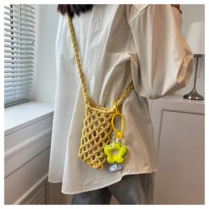 Detail of yellow hand-woven mini crossbody bag with floral charm on white shirt