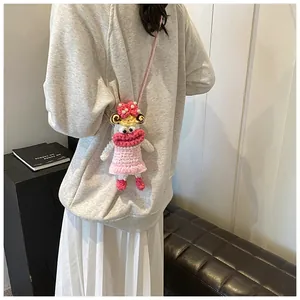 Detailed shot of a pink hand-knitted cartoon doll crossbody bag on a model