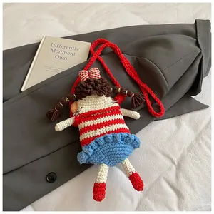 Close-up of handmade crochet doll crossbody bag with red checkered bow and striped shirt