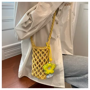 Detail of yellow hollow knit mini crossbody bag with sunflower charm and woven strap