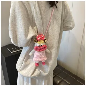 Detail of handmade crochet doll bag with large pink lips and pearl accents worn as crossbody