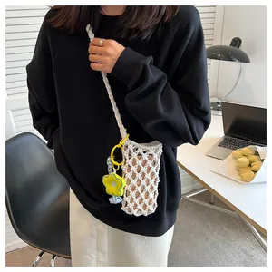 Close-up of white crochet hollow-out phone bag with a yellow flower charm on a model