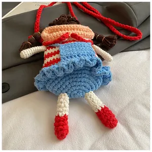 Detail of handmade crochet cartoon doll crossbody bag with red stripes and blue skirt