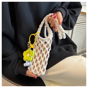 Close-up of white hand-woven mini bag with hollow mesh and yellow flower pendant