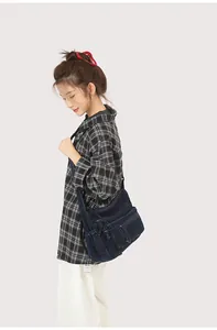 Detail view of a vintage navy denim crossbody bag with multiple zip pockets on model