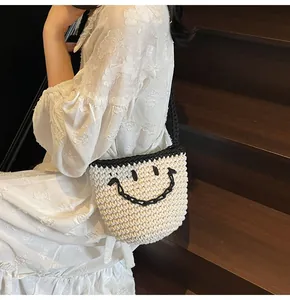 Close-up of handmade woven bucket bag with large black smiley face and shoulder strap