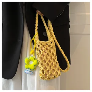 Detail of yellow woven mobile phone bag featuring hollow crochet texture and a flower charm