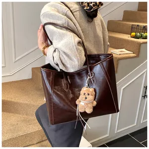 Détail du grand sac cabas en cuir marron foncé avec surpiqûres et breloque ours en peluche
