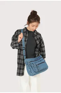 Detail of the washed blue denim messenger bag showing multi-zipper pockets and texture
