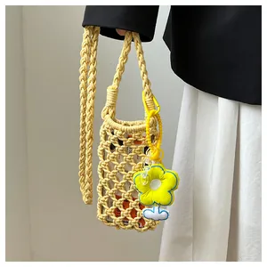Detail of yellow hollow knit phone bag with floral charm and woven strap